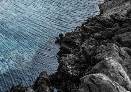 A rocky coastline meets the deep blue ocean