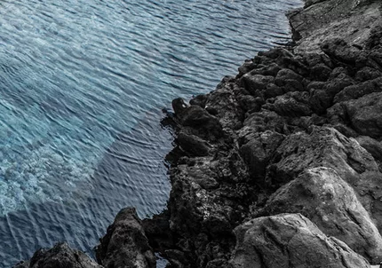 A rocky coastline meets the deep blue ocean
