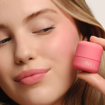 Model holding ARMANI Beauty DOLCI blush near her cheek, showing a fresh pink blush result