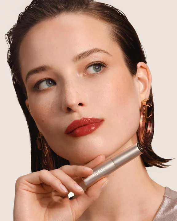Armani Prisma Flash Scarlet Flash lipstick, showcased during application, emphasizing its bold, vibrant red pigment and sleek tube.