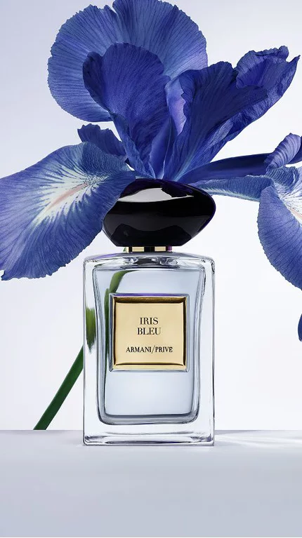 Bottle of Armani/Prive Iris Bleu agaisnt a light blue background with iris flower.