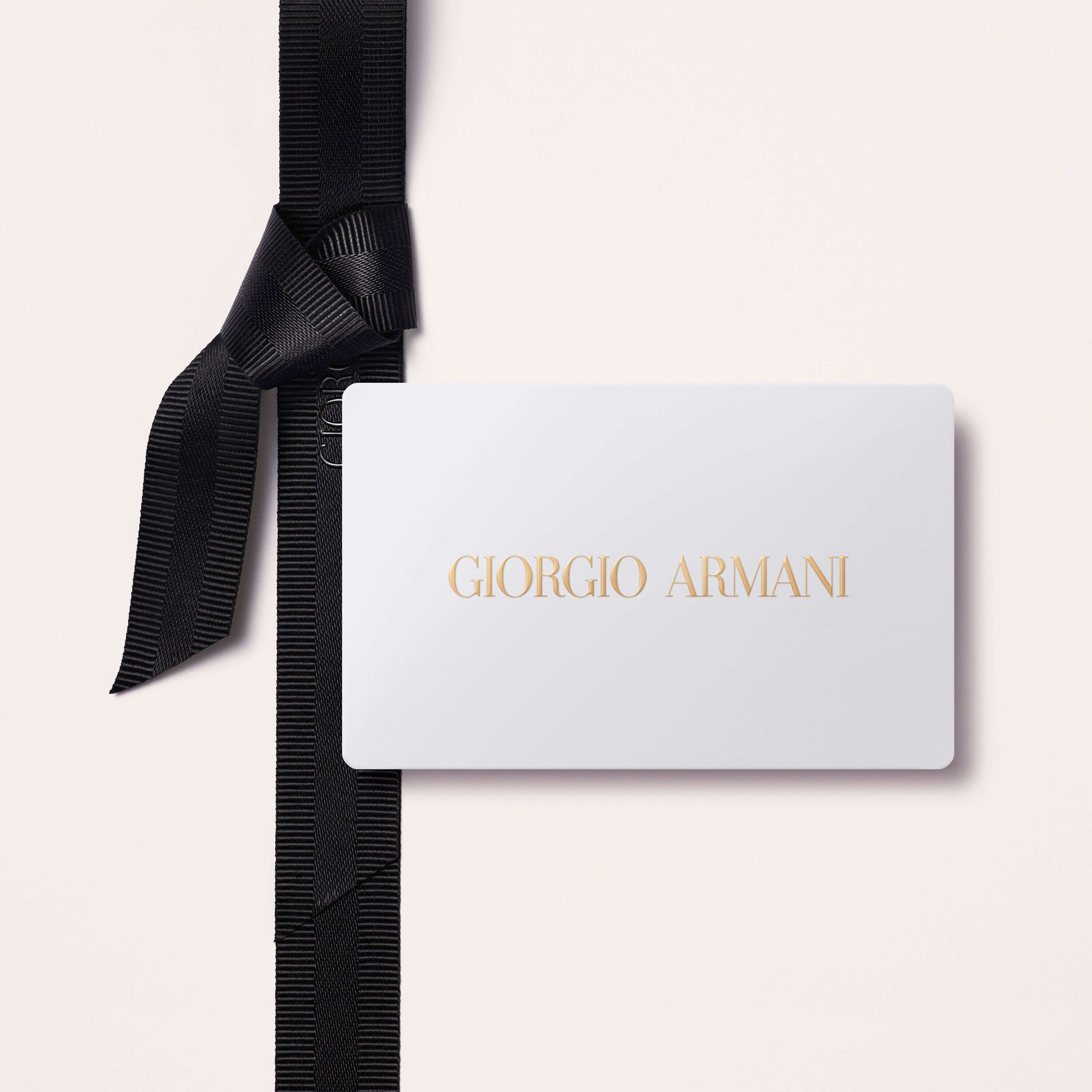 A pale pink box gift tied with a black bow with an Armani gift card placed on top