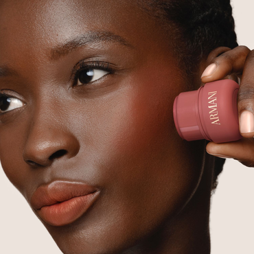 Model applying deep pink Armani Beauty Dolci Blush, a cream-to-powder blush with a natural finish.