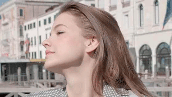 Woman with long blonde hair basking her face in sun at Venice Film Festival 