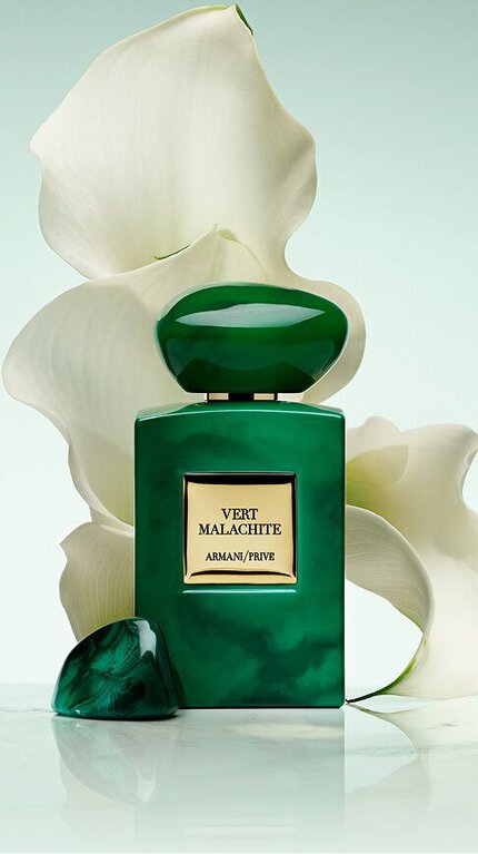 Bottle of Armani/Prive Vert Malachite against a light green background with a white flower.