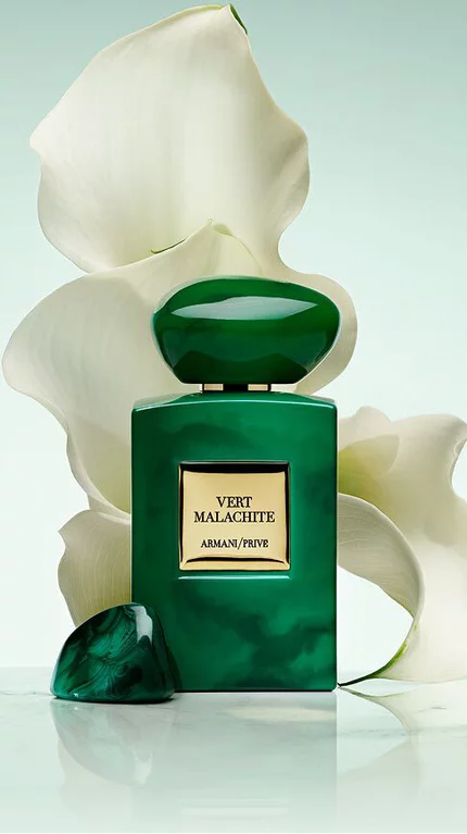Bottle of Armani/Prive Vert Malachite against a light green background with a white flower.