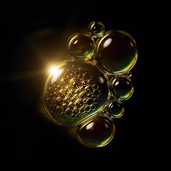 gold and green shimmering serum bubble droplets with light shining through on black background