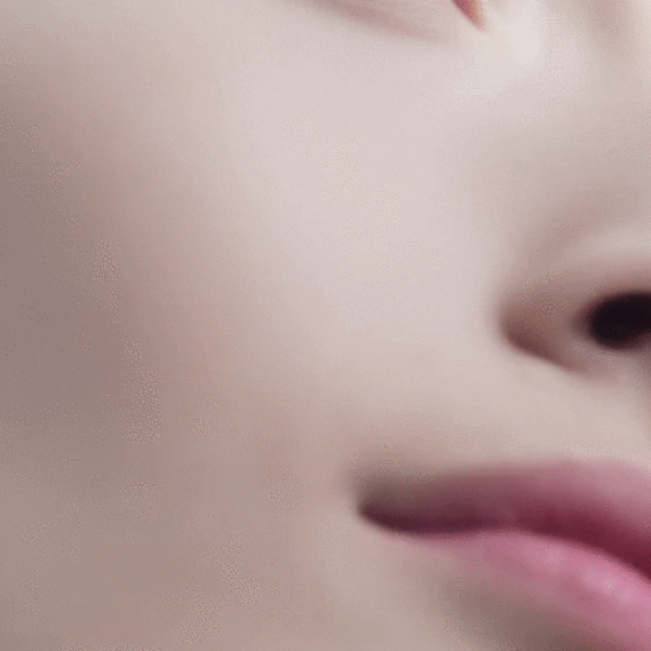 video image of woman that starts as extreme closeup of side of cheek then revealing her head and bare shoulders with minimal makeup looking ahead